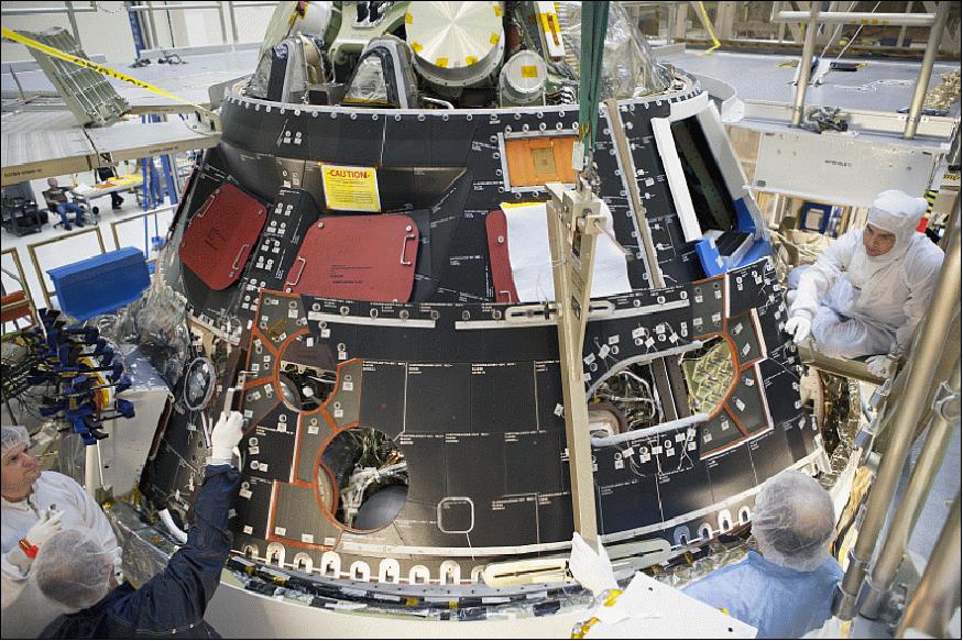 Figure 6: Inside the Operations and Checkout Building high bay at NASA's Kennedy Space Center in Florida, technicians dressed in clean-room suits, install a back shell tile panel onto the Orion crew module (image credit: NASA)