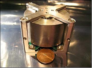 Figure 5: Photo of the reaction wheel shown with a penny for scale (image credit: UTIAS/SFL)