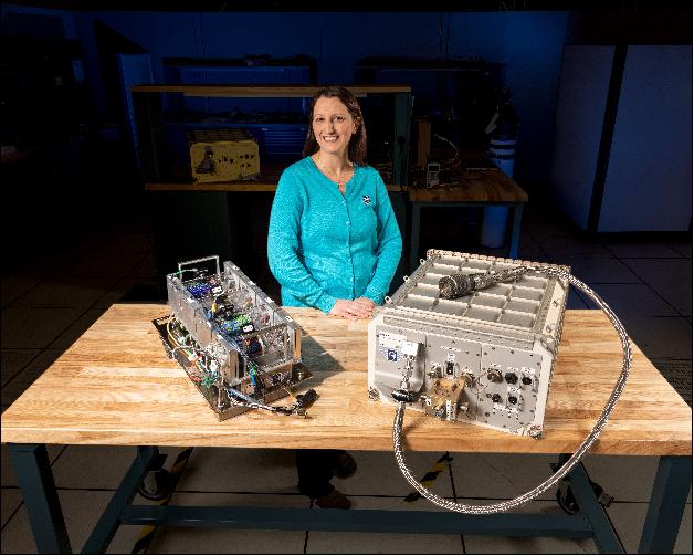 Figure 3: Hermes Principal Investigator, Kristen John, stands in front of the Hermes hardware. On the right is the Hermes Facility, and on the the left is Cassette-1, the first set of science experiments to be installed in the Facilit (image credit: NASA)