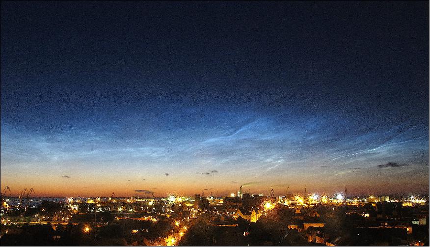 Figure 29: Noctilucent clouds over the city of Wismar, Germany in July 2015. Tropospheric clouds are visible as dark patches near the horizon (image credit: Leibniz Institute of Atmospheric Physics)