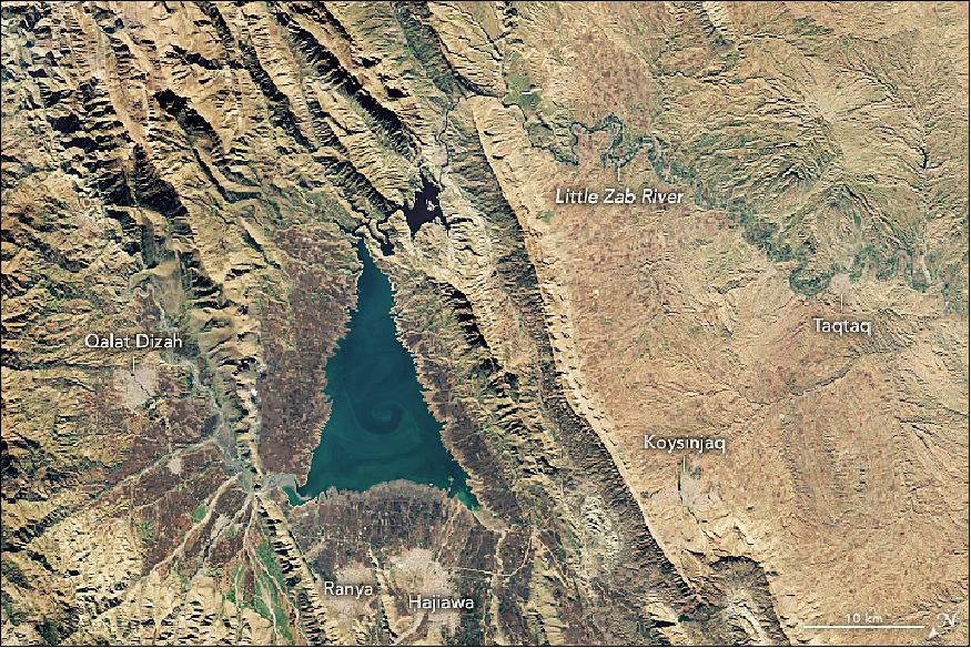 Figure 2: This image shows a wider view of the lake, acquired by the Operational Land Imager on Landsat-8 on November 20, 2018. Situated in the Zagros Mountains, the bright blue lake stands out against the surrounding yellow and green mounds. The swirls in the lake might be a phytoplankton bloom or suspended sediment (image credit: NASA Earth Observatory, image by Lauren Dauphin, using Landsat data from the U.S. Geological Survey, Story by Kasha Patel)