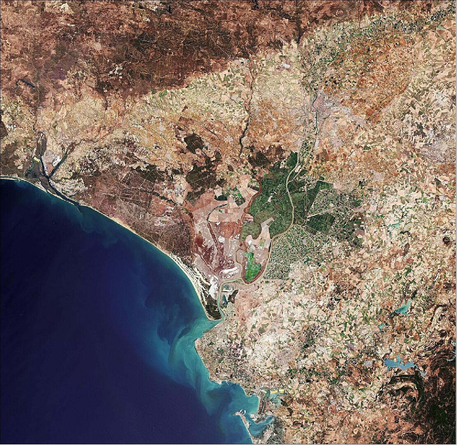 Figure 5: Seville, visible towards the top right of this image, is the capital of Andalusia and the fourth largest city in Spain. An inland port, it lies on the Guadalquivir River and while the original course of the river is visible snaking through the city on the right, we can see where water has also been redirected into a straighter course on the left. At over 650 km long, the Guadalquivir is one of the longest rivers in Spain, extending way beyond the frame of this image. Nevertheless, it can be seen winding its course all the way from the top right of the image, just south of the Sierra Norte mountain range, to the Gulf of Cádiz where it empties into the Atlantic Ocean. On route, this major river serves as a source for irrigation – here noticeable in the top right of the image, but mainly to the south of Seville where large green agricultural fields appear in sharp contrast to the surrounding drier brown land. This image, captured on 21 June 2019 with Sentinel-2, is also featured on the Earth from Space video program (image credit: ESA, the image contains modified Copernicus Sentinel data (2019), processed by ESA, CC BY-SA 3.0 IGO)