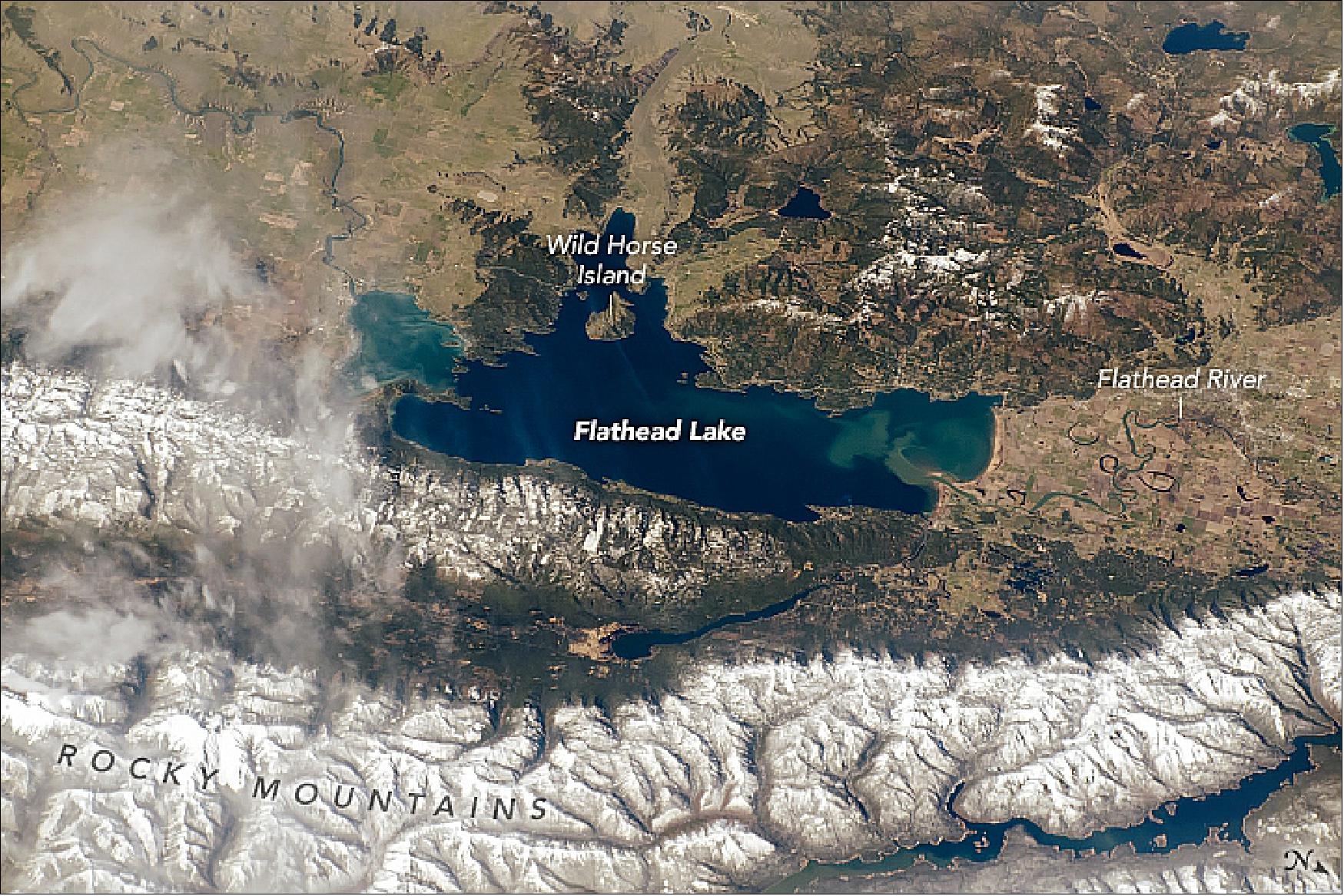 Figure 93: Flathead is located within a depression known as the Rocky Mountain Trench, and it is one of the largest freshwater lakes west of the Mississippi River in the continental United States. The lighter-toned parts of the lake are due to the inflow of sediment from seasonal snow melt. The meandering Flathead River, which flows south into the lake, has created multiple sloughs (also known as oxbows) along its course (image credit: Astronaut photograph ISS059-E-36857 was acquired on April 29, 2019, with a Nikon D5 digital camera using a 240 mm lens and is provided by the ISS Crew Earth Observations Facility and the Earth Science and Remote Sensing Unit, Johnson Space Center. The image was taken by a member of the Expedition 59 crew)