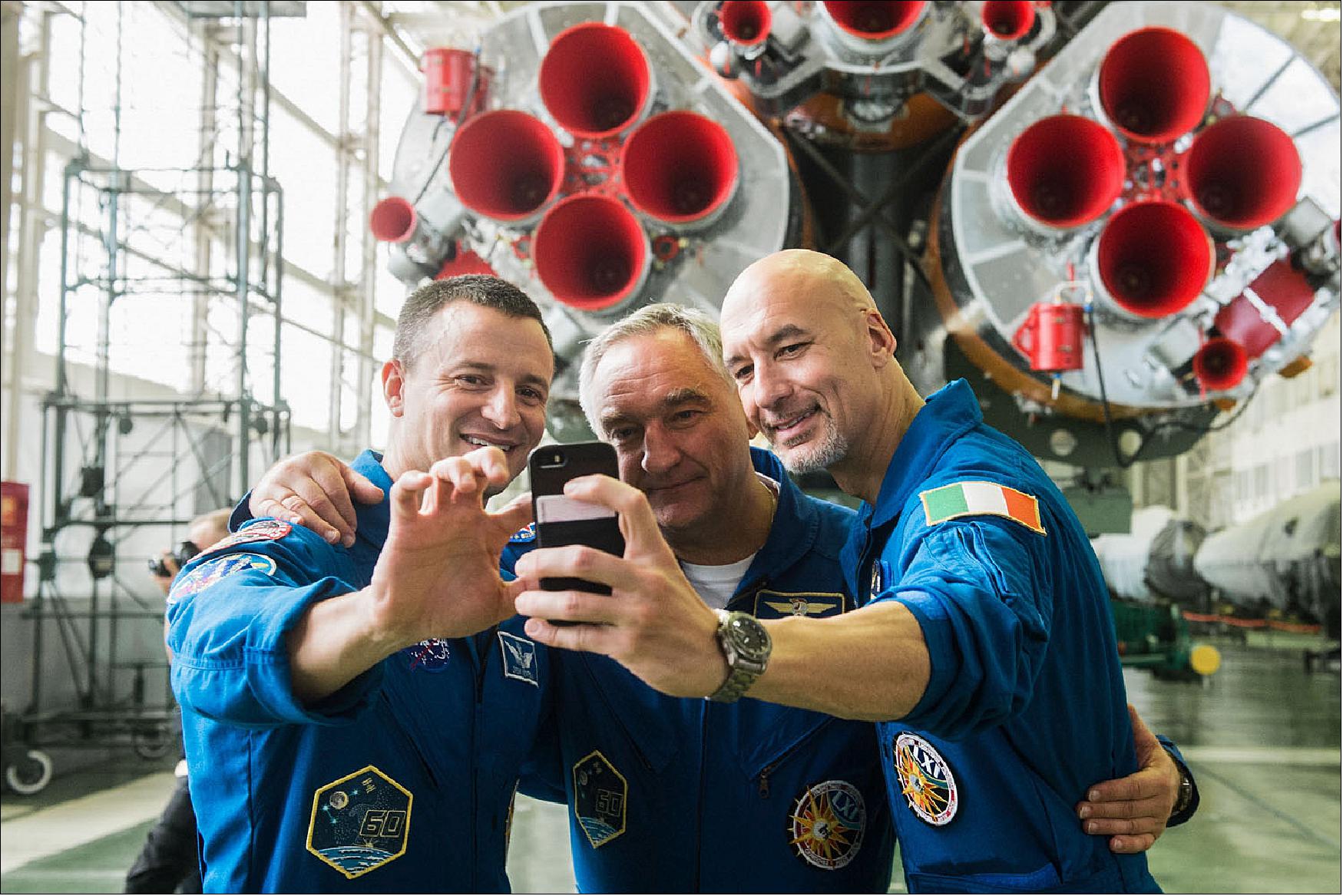 Figure 74: In the Integration Building at the Baikonur Cosmodrome in Kazakhstan, Expedition 60 crewmembers Drew Morgan of NASA (left), Alexander Skvortsov of Roscosmos (center) and Luca Parmitano of the European Space Agency (right) pose for a selfie in front of the first stage engines of their Soyuz booster on 16 July as part of pre-launch preparations (image credit: GCTC, A. Shelepin)