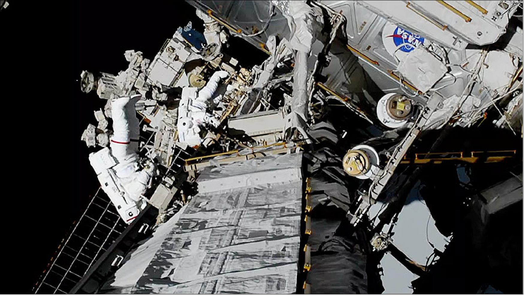 Figure 31: NASA spacewalkers Christina Koch (foreground, suit with red stripe) and Jessica Meir (suit with no stripes) replaced a failed BCDU (Battery Charge-Discharge Unit) with a new one during a 7-hour, 17-minute spacewalk (image credit: NASA TV)