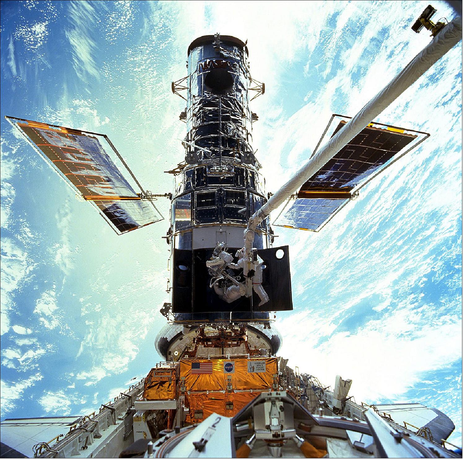 Figure 59: Hubble berthed in the Space Shuttle bay during Servicing Mission 3A. Astronauts Steven L. Smith, and John M. Grunsfeld, appear as small figures in this wide scene photographed during EVA (Extravehicular Activity), image credit: NASA/ESA