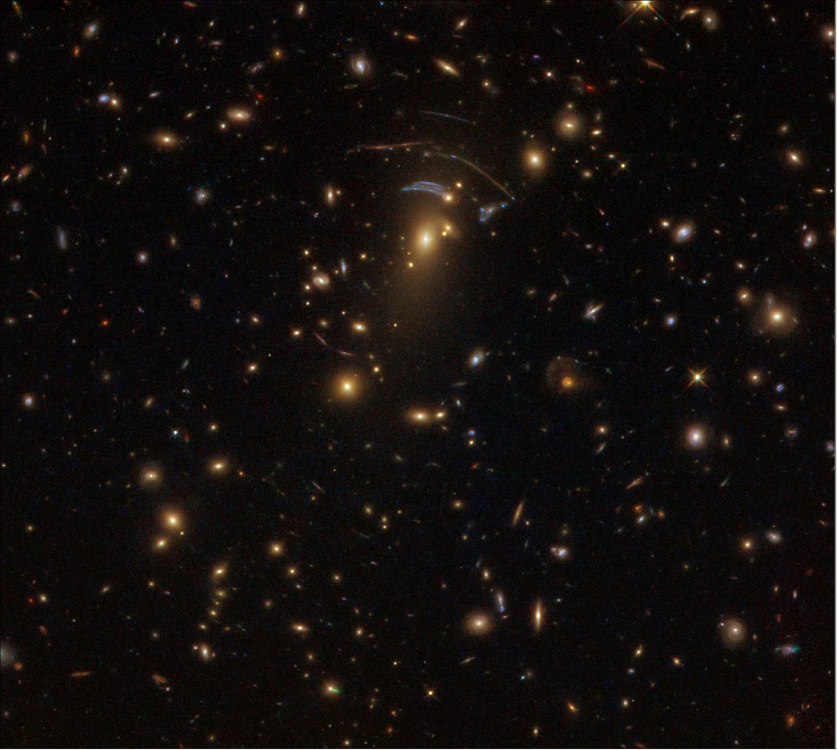 Figure 21: This image was taken with the NASA/ESA Hubble Space Telescope’s Wide Field Camera 3 (WFC3) and shows an object named SDSS J1138+2754. It acts as a gravitational lens illustrating the true strength of gravity: A large mass — a galaxy cluster in this case — is creating such a strong gravitational field that it is bending the very fabric of its surroundings. This causes the billion-year-old light from galaxies sitting behind it to travel along distorted, curved paths, transforming the familiar shapes of spirals and ellipticals (visible in other parts of the image) into long, smudged arcs and scattered dashes (image credit: ESA/Hubble & NASA; Acknowledgement: Judy Schmidt; CC BY 4.0)