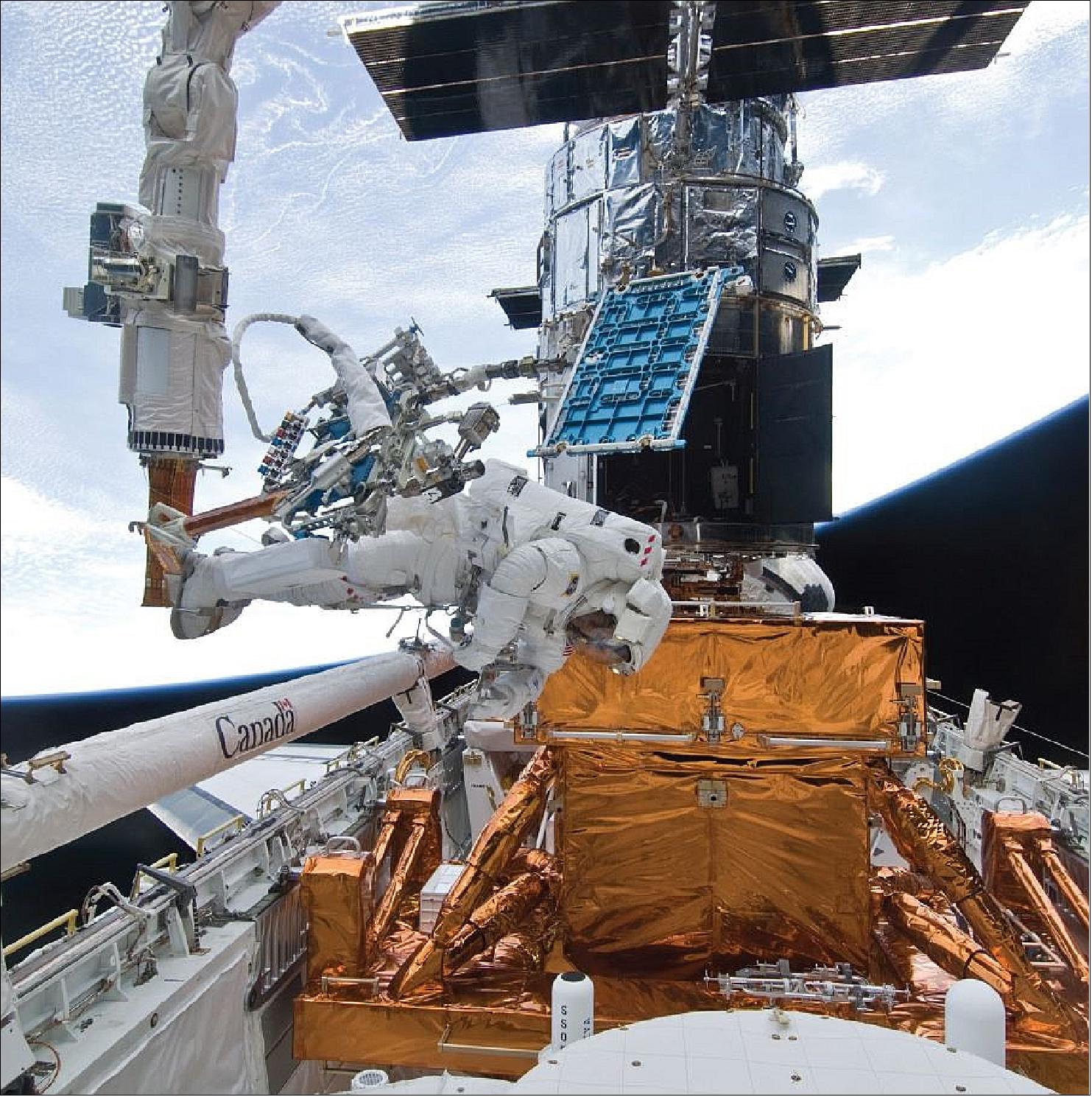 Figure 70: With his feet firmly anchored on the shuttle’s robotic arm, astronaut Mike Good maneuvers to retrieve the tool caddy required to repair the Space Telescope Imaging Spectrograph during the final Hubble servicing mission in May 2009. Periodic upgrades have kept the telescope equipped with state-of-the-art instruments, which have given astronomers increasingly better views of the cosmos (image credit: NASA)