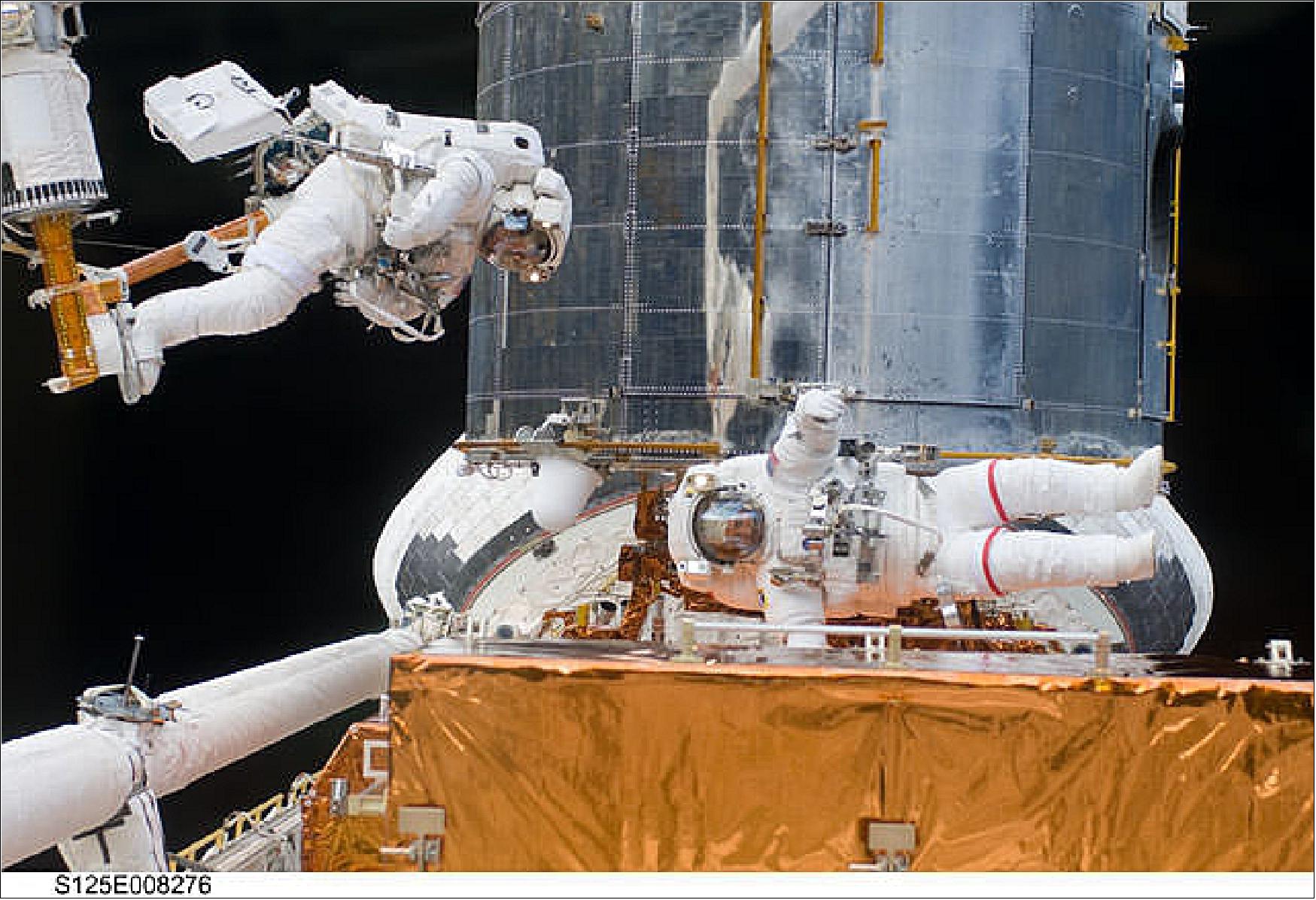 Figure 69: STS-125 astronauts John Grunsfeld and Andrew Feustel work together on EVA 3 to navigate the exterior of the Hubble Space Telescope on the end of the remote manipulator system arm, controlled from inside Atlantis' crew cabin (image credit: NASA)