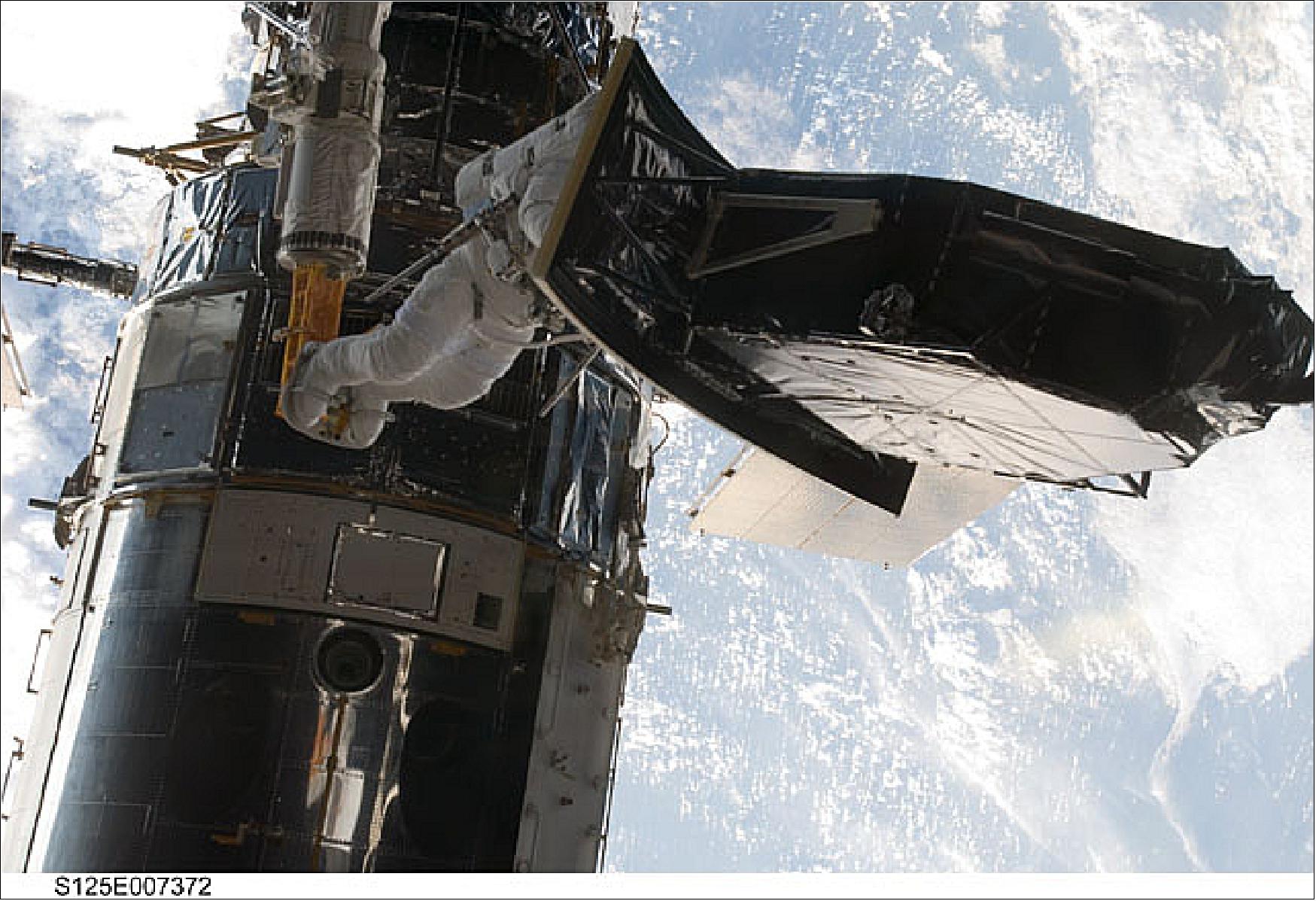 Figure 67: Andrew Feustel hauls the new WFC3 on the robotic arm, to install the camera on Hubble. (image credit: NASA)