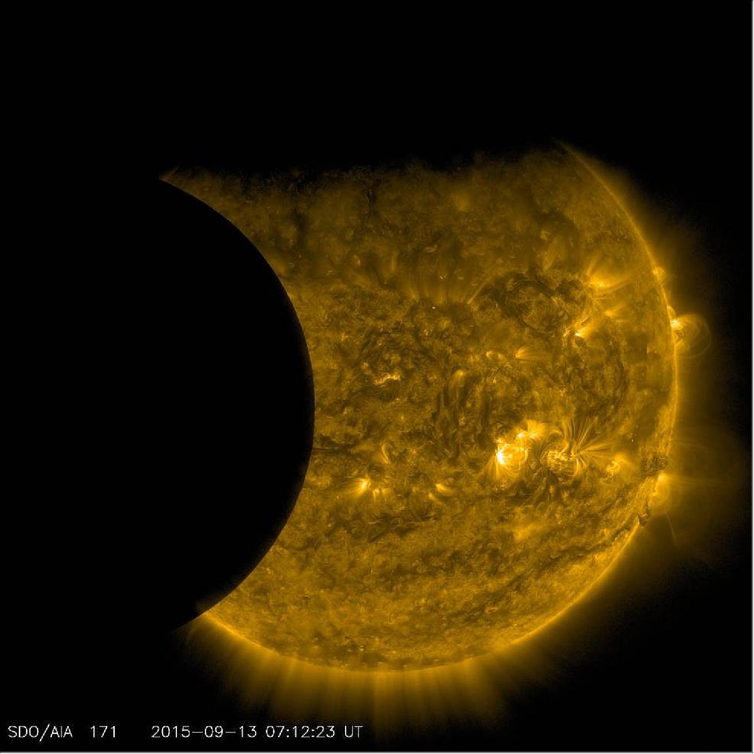 Figure 18: SDO captured this image of Earth and the moon transiting the sun together on Sept. 13, 2015. The edge of Earth, visible near the top of the frame, appears fuzzy because Earth’s atmosphere blocks different amounts of light at different altitudes. On the left, the moon’s edge is perfectly crisp, because it has no atmosphere. This image was taken in extreme ultraviolet wavelengths of 171Å. Though this light is invisible to our eyes, it is typically colorized in gold (image credit: NASA, SDO)