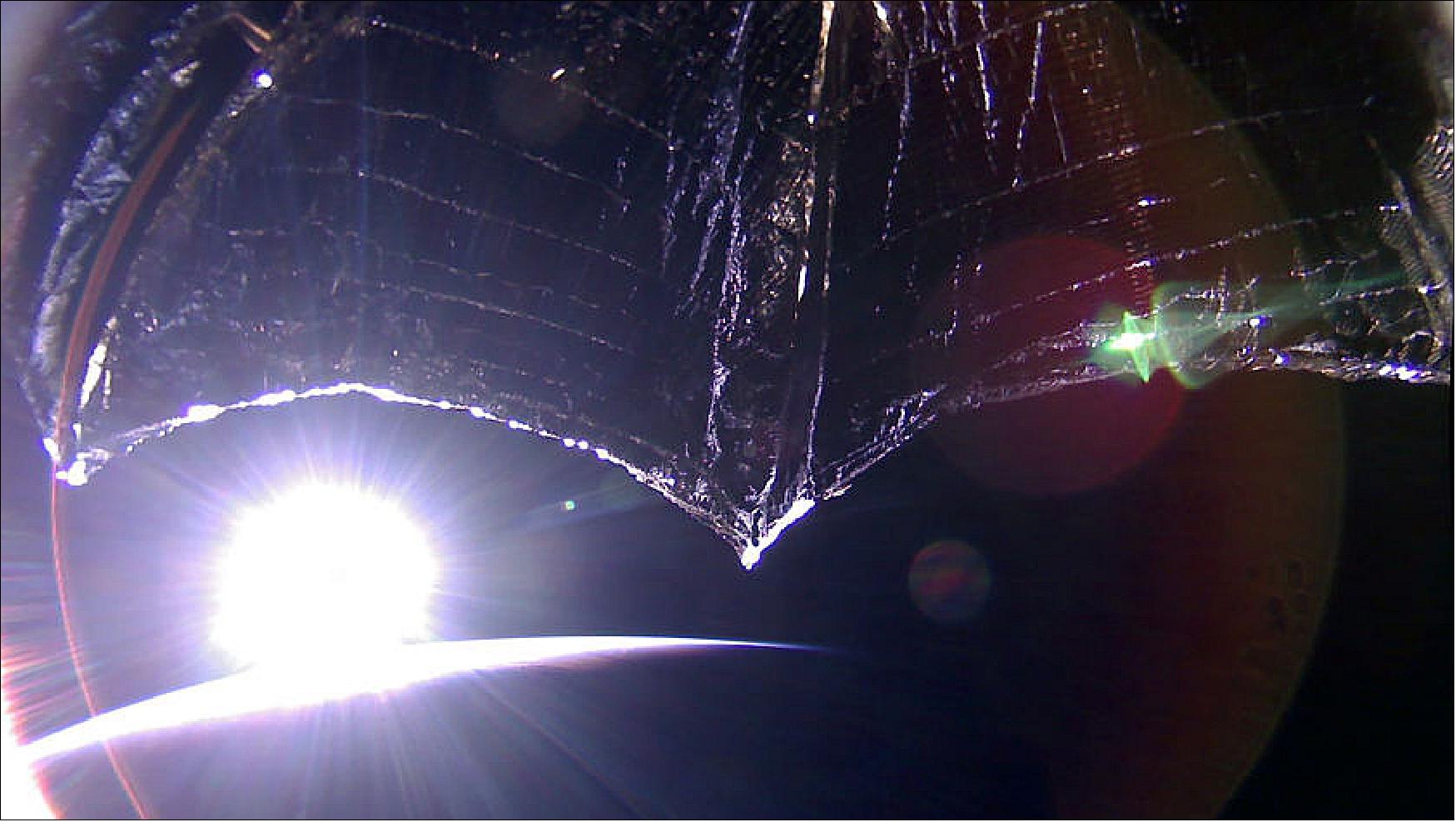 Figure 8: LightSail 2 Orbital Sunrise: The Sun rises over the horizon in this image from LightSail-2 captured on 28 September 2019. The sail appears curved due to the spacecraft's 185-degree fisheye camera lens. The image has been color corrected and some of the distortion has been removed (image credit: The Planetary Society)