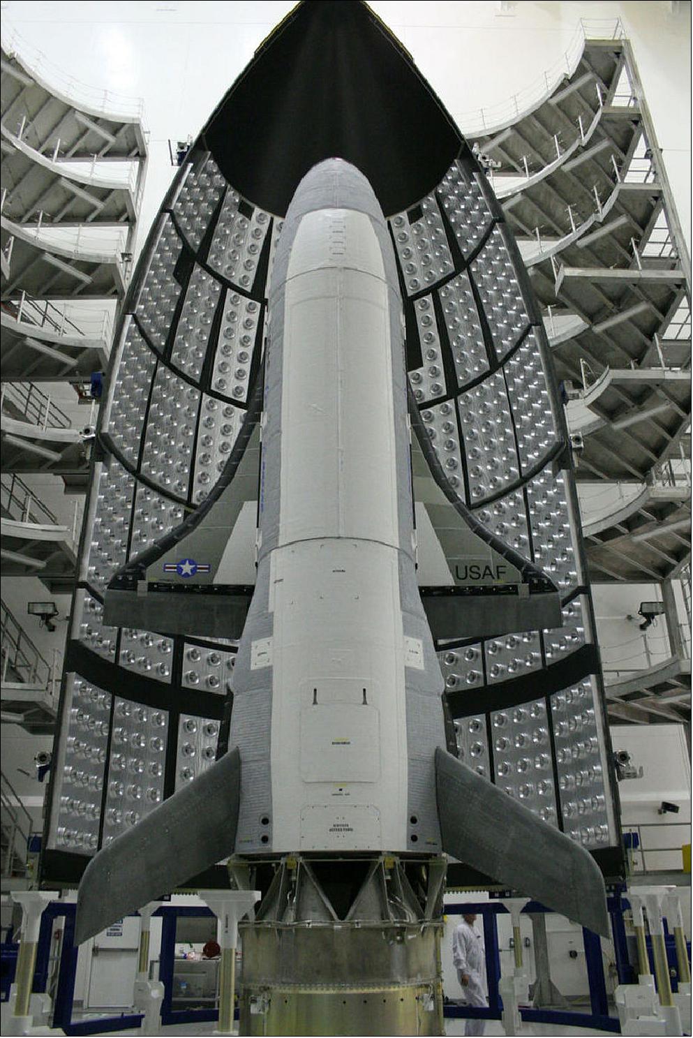 Figure 3: The first X-37B Orbital Test Vehicle waits in the encapsulation cell of the EELV (Evolved Expendable Launch Vehicle) April 5, 2010, at the Astrotech facility in Titusville, Fla. Half of the Atlas-V 5 m fairing is visible in the background. The OTV-1 launch on April 22, 2010 on a ULA vehicle from KSC, FL (image credit: USAF)