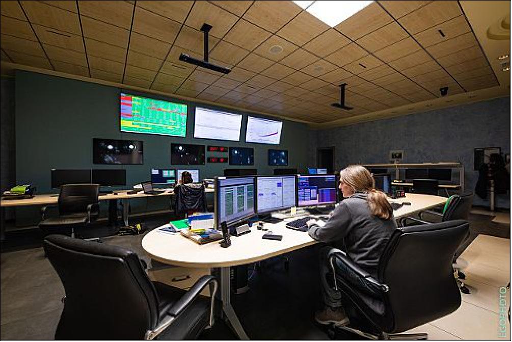 Figure 10: The control room of Advanced Virgo at the European Gravitational Observatory, near Pisa (Italy). Shown in the foreground is an EGO operator working on shift to keep the detector running. Usually a lively environment, the control room is now minimally populated because of the COVID-19 pandemic. The image shows only one Virgo scientist working, Julia Casanueva, in the control room along with the EGO operator, Fabio Gherardini (image credit: EGO/Virgo Collaboration)