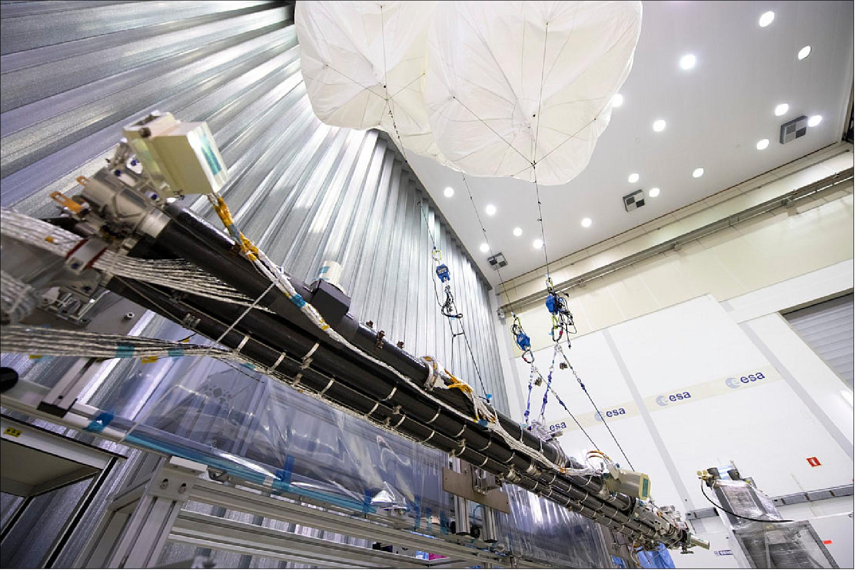 A test version of the 10.5 m long magnetometer boom built for ESA's mission to Jupiter, developed by SENER in Spain, seen being tested at ESA's Test Center in the Netherlands, its weight borne by balloons (image credit: ESA–G. Porter, CC BY-SA 3.0 IGO)
