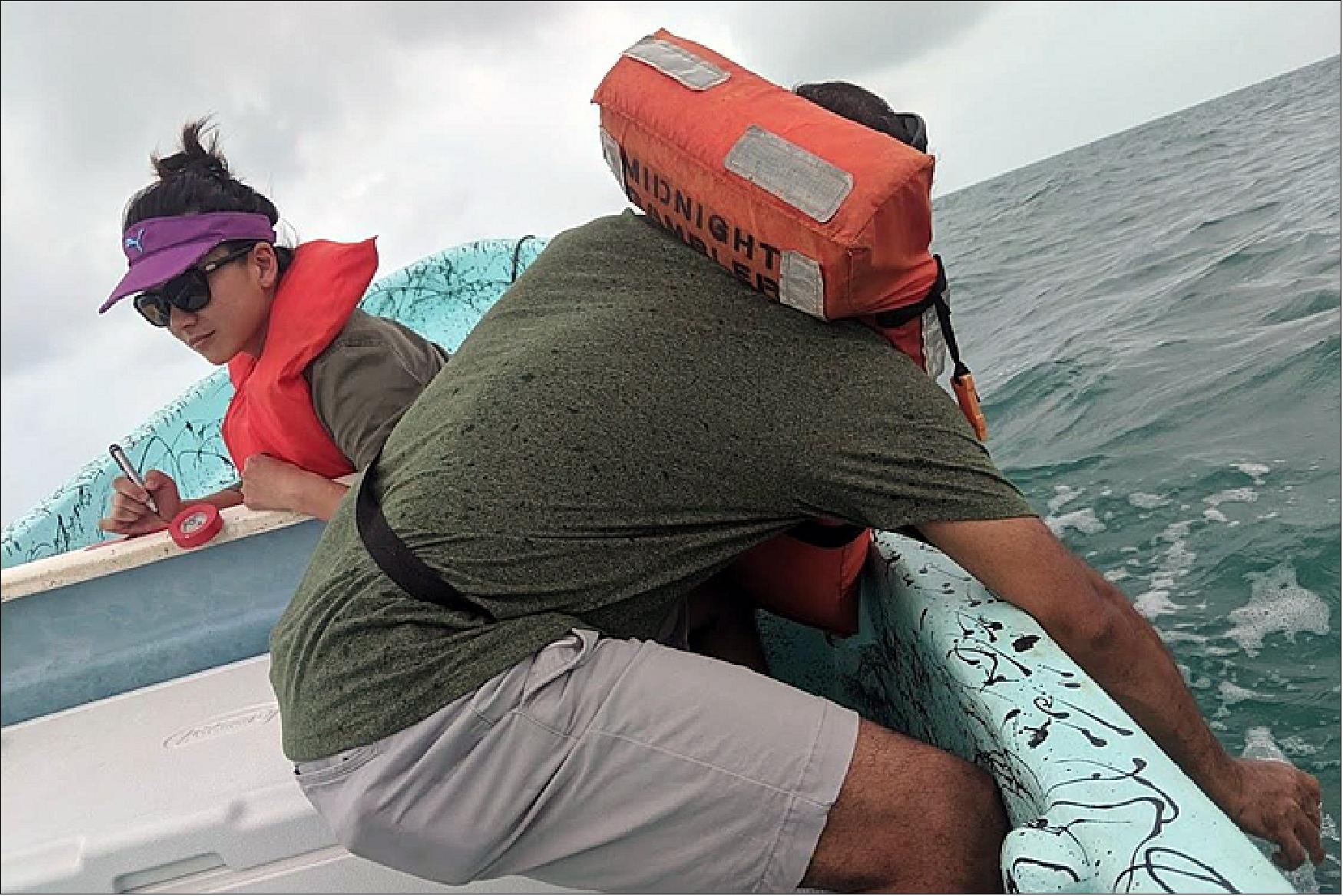 Figure 74: Project co-Investigator Christine Lee (left) of JPL writing the label for a sea water sample being collected by co-Investigator Deepak Mishra (right) of the University of Georgia (image credit: NASA Earth Observatory)