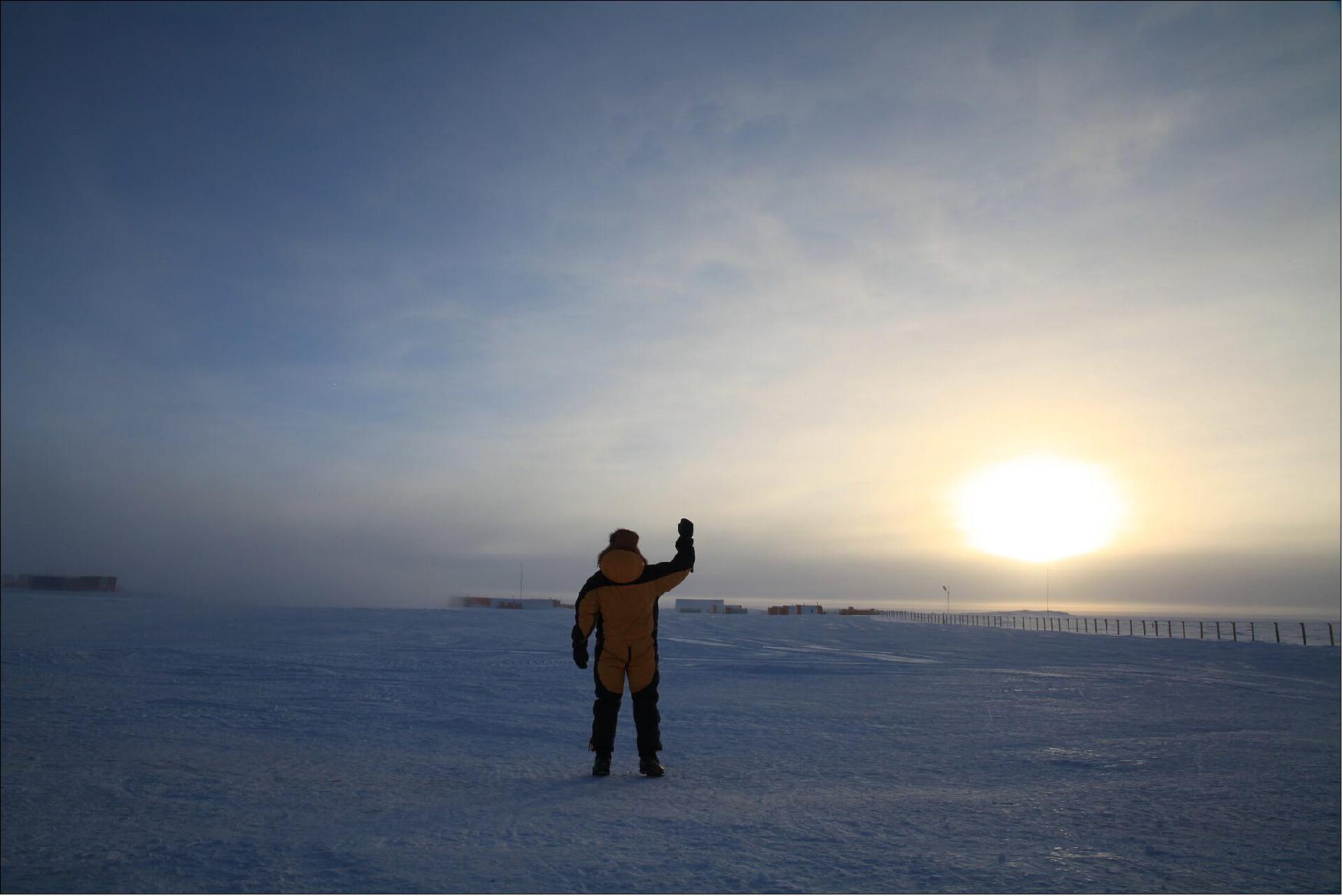 Figure 88: Concordia crewmember waves to the Sun in Antarctica. So far from the equator, the days and nights can be long – very long. The winter night lasts up to four months when the Sun does not rise above the horizon (image credit: ESA/IPEV/PNRA–A. Kumar)