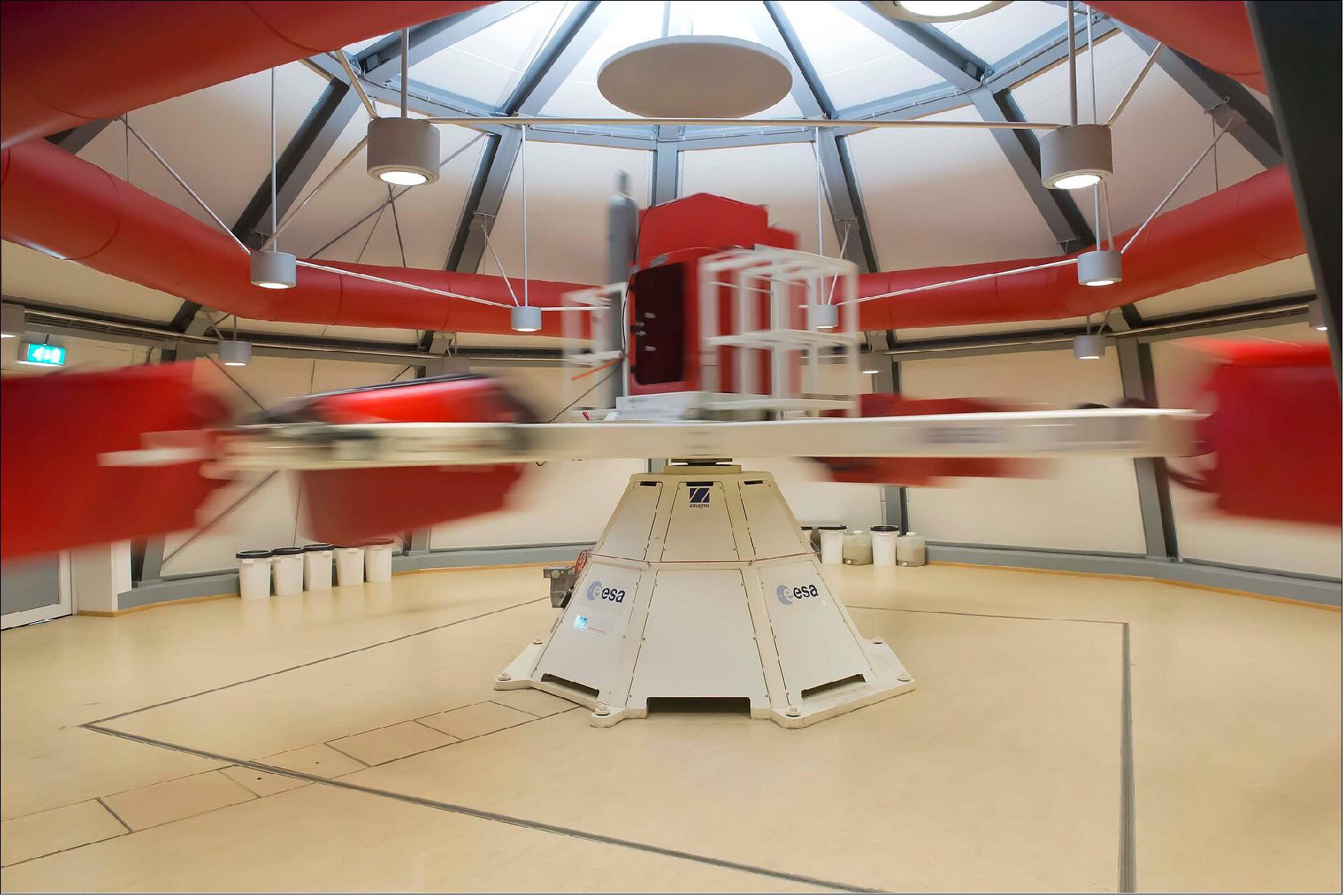 Figure 106: ESA's Large Diameter Centrifuge at the Agency's technical heart in the Netherlands is seen running here at full speed. The 8-m diameter four-arm centrifuge gives researchers access to a range of hypergravity environments up to 20 times Earth's gravity for weeks or months at a time. At its fastest, the centrifuge rotates at up to 67 revs per minute, with its six gondolas placed at different points along its arms weighing in at 130 kg, and each capable of accommodating 80 kg of payload. (image credit: ESA –A. Le Floc'h)