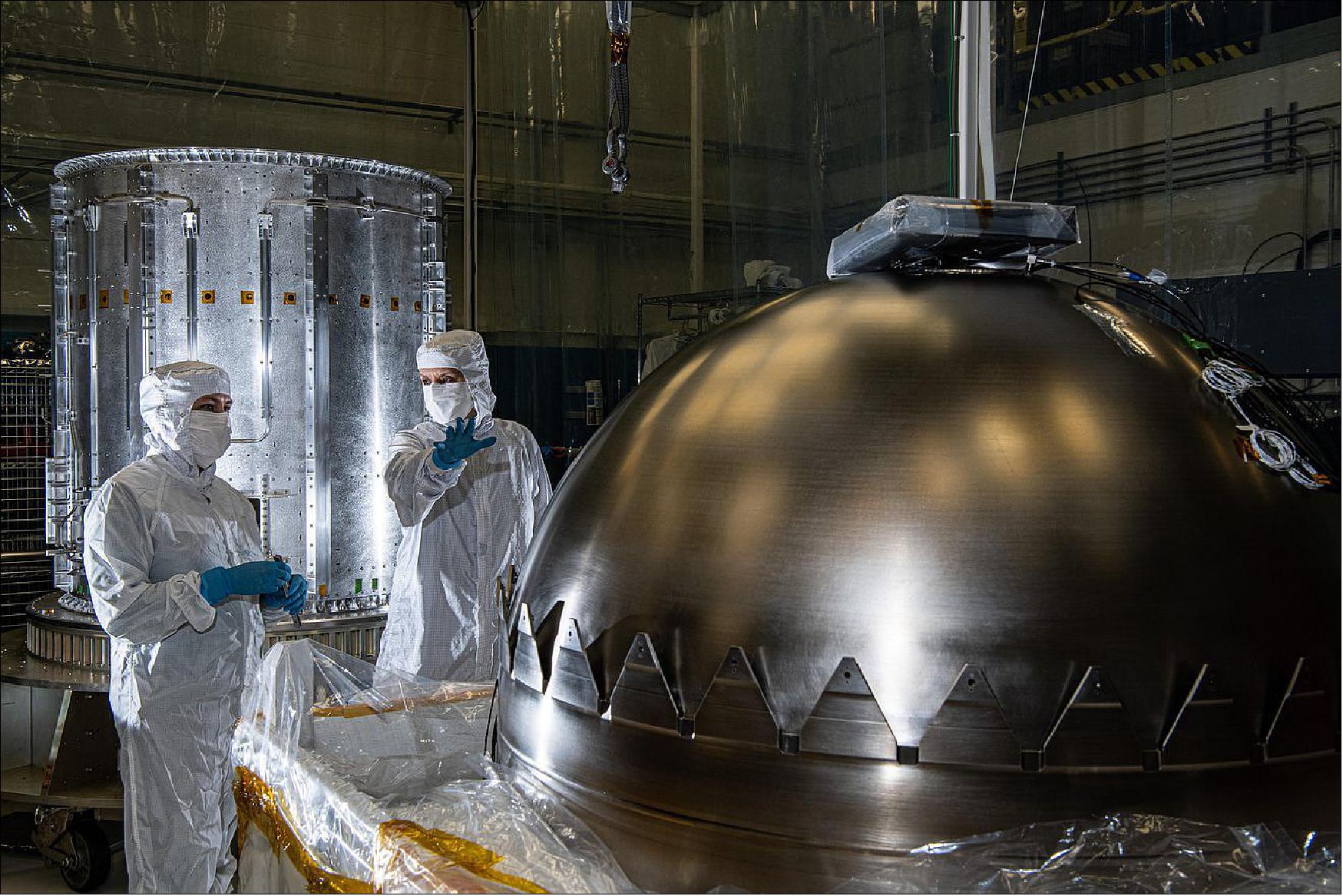 Figure 4: Prepping Europa Clipper's Propulsion Tanks. Contamination control engineers in a clean room at NASA's Goddard Space Flight Center in Greenbelt, Maryland, evaluate a propellant tank before it is installed in NASA's Europa Clipper spacecraft. The tank is one of two that will be used to hold the spacecraft's propellant. It will be inserted into the cylinder seen at left in the background, one of two cylinders that make up the propulsion module (image credit: NASA/GSFC Denny Henry)