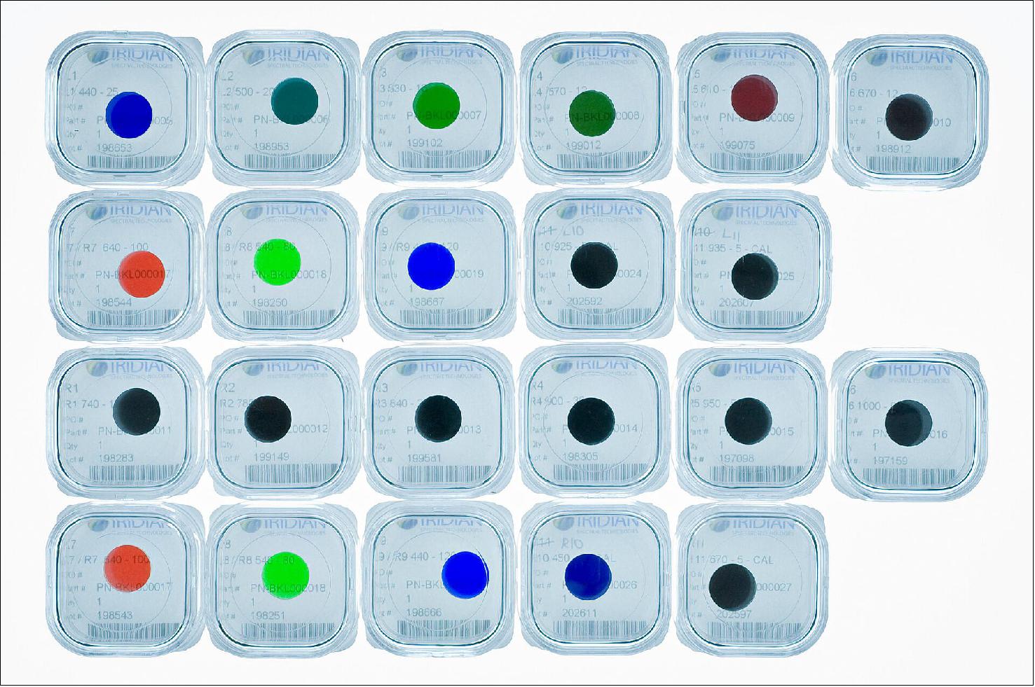 Figure 21: ExoMars PanCam filters. This may look like a collection of colorful contact lenses and in some respects there are some similarities: these are the filters through which the ExoMars rover – Rosalind Franklin – will view Mars in visible and near infrared wavelengths. - They are pictured here in their individual transport cases, before they were installed in the filter wheels of the Panoramic Camera, PanCam, which comprises two wide-angle cameras and a high-resolution camera. The wide-angle cameras are mounted at each end of the PanCam unit and form a stereo pair. Each camera has a filter wheel with 11 positions. Red, green and blue broadband imaging filters for color stereo imaging are common to both left and right cameras; the remaining eight are different between left and right to provide the range of filters needed for geological and solar imaging. The geology filters have been specifically selected to identify water-rich minerals and clays on Mars. - PanCam also hosts a high-resolution color camera and, sitting on a mast 2 m above the martian surface, will be fundamental in the day-to-day scientific operations of the rover, its images essential to assist with scientific decisions on where to drive to next, and where to target its drill. The rover will be the first with the capability to drill 2 m below the surface to retrieve samples for analysis in its onboard laboratory, seeking signs of life past or present. Combined with observations with its spectrometers, close-up imager, sub-surface sounding radar and neutron detector, the ExoMars rover has a powerful payload to explore the surface and subsurface of Mars. - The filters of the wide-angle camera shown here were integrated into their filter wheels in 2018 and completed calibration testing on 11 May 2019. Just last week the entire PanCam instrument was shipped from University College London’s Mullard Space Science Laboratory and delivered to Airbus, Stevenage, in the UK, where it will soon be built into the rover, giving Rosalind Franklin rover her science eyes. (image credit: M. de la Nougerede, UCL/MSSL)