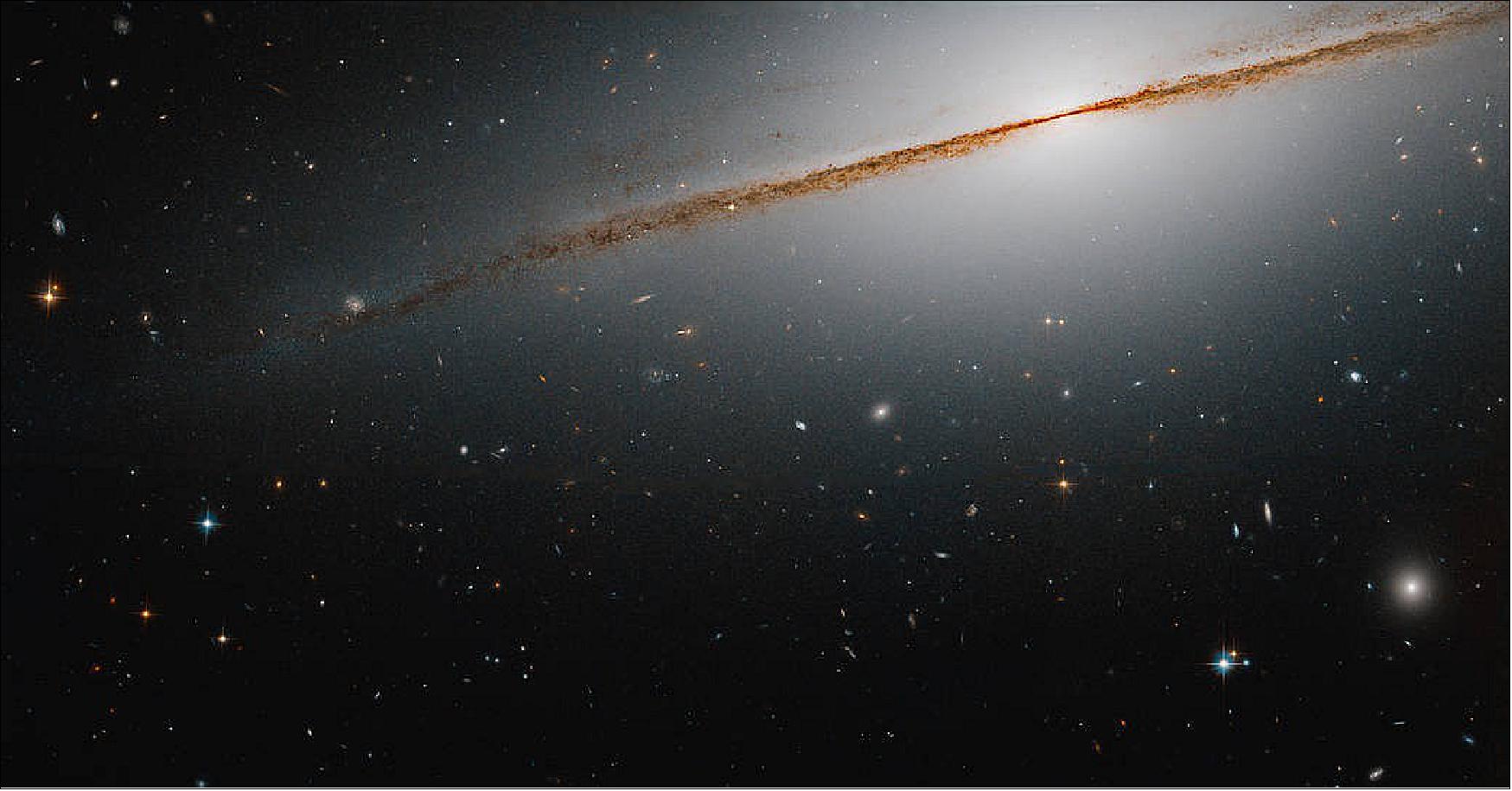 Figure 42: This image of the Little Sombrero is a combination of visible and infrared observations captured by Hubble’s Advanced Camera for Surveys in 2006. The observations were taken to assist astronomers in studying the galaxy’s stellar populations, and to help shed light on the evolution of this galaxy and others like it. Edge-on galaxy, with a distinctive dust lane, extending from upper right to middle-left of the image. Distant galaxies dot the scene [image credit: NASA, ESA, and R. de Jong (Leibniz-Institut fur Astrophysik Potsdam); Image processing: G. Kober (NASA Goddard/Catholic University of America)]