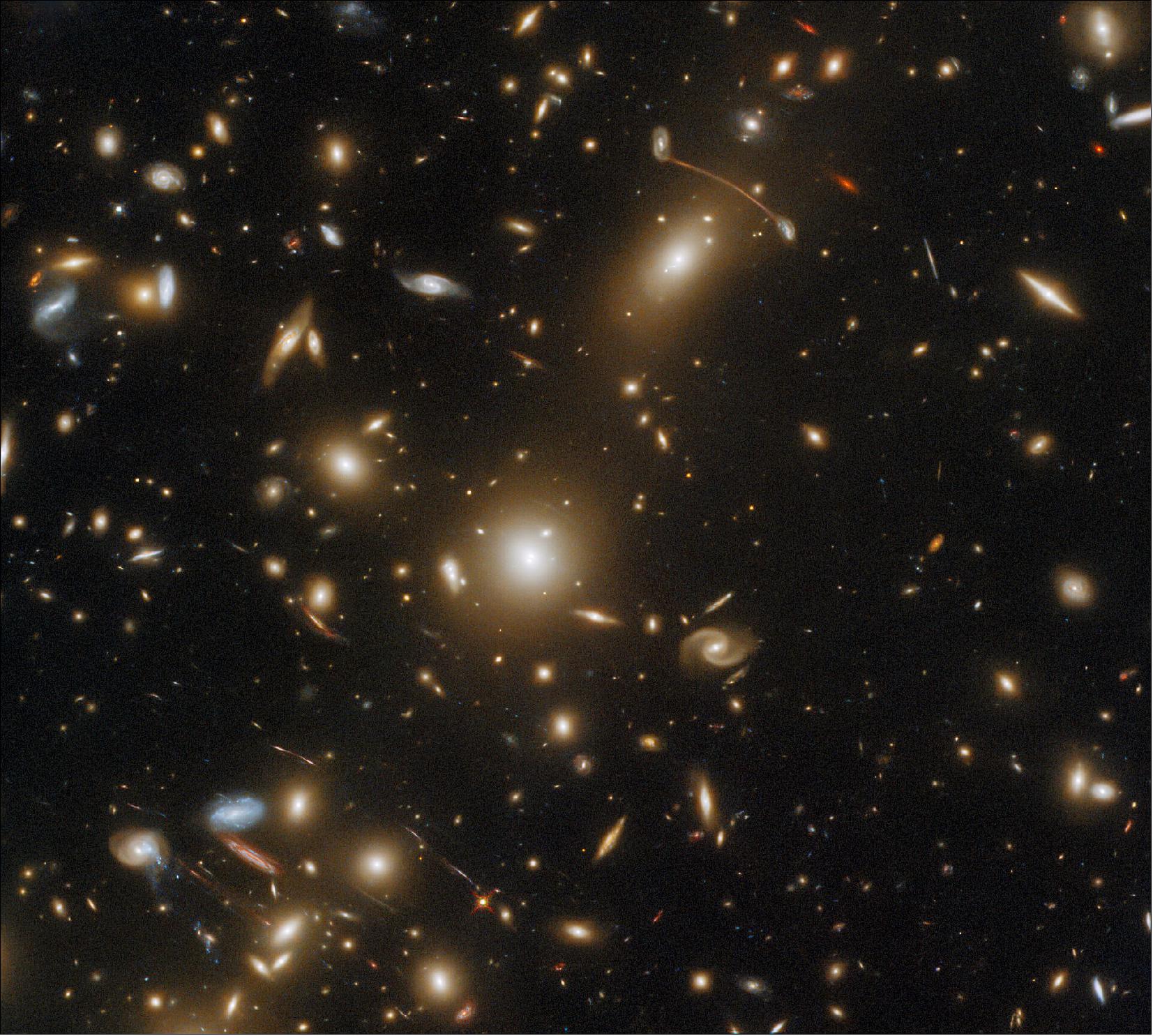 Figure 15: This image is filled with streaks of light, which are actually the images of distant galaxies. The streaks are the result of gravitational lensing, an astrophysical phenomenon that occurs when a massive celestial body such as a galaxy cluster distorts spacetime sufficiently strongly to affect the path of light passing through it — almost as if the light were passing through a gigantic lens. Gravitational lensing comes in two varieties — strong and weak — and both can give astronomers an insight into the distribution of mass within a lensing galaxy cluster such as Abell 1351 (image credit: ESA/Hubble & NASA, H. Ebeling; Acknowledgement: L. Shatz; CC BY 4.0)