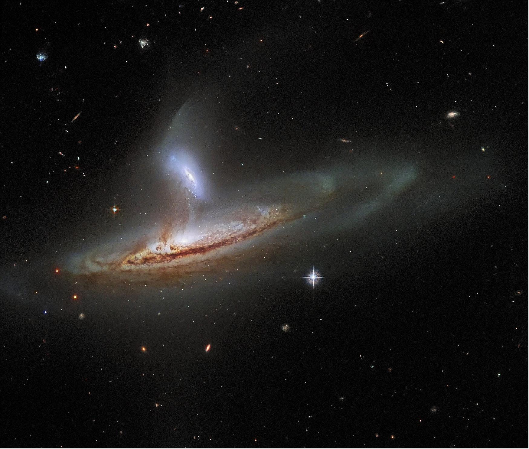 Figure 73: The subject of this image is named Arp 282, an interacting galaxy pair that is composed of the Seyfert galaxy NGC 169 (bottom) and the galaxy IC 1559 (top). If you’re interested in learning more about Seyfert galaxies, you can read about the Seyfert galaxy NGC 5728 here. Interestingly, both of the galaxies comprising Arp 282 have monumentally energetic cores, known as active galactic nuclei (AGN), although it is difficult to tell that from this image. This is actually rather fortunate, because if the full emission of two AGNs was visible in this image, then it would probably obscure the beautifully detailed tidal interactions occurring between NGC 169 and IC 1559. Tidal forces occur when an object’s gravity causes another object to distort or stretch. The direction of the tidal forces will be away from the lower-mass object and towards the higher mass object. When two galaxies interact, gas, dust and even entire solar systems will be drawn away from one galaxy towards the other by these tidal forces. This process can actually be seen in action in this image — delicate streams of matter have formed, visibly linking the two galaxies (image credit: ESA/Hubble & NASA, J. Dalcanton, Dark Energy Survey, DOE, FNAL/DECam, CTIO/NOIRLab/NSF/AURA, SDSS; CC BY 4.0 Acknowledgement: J. Schmidt)