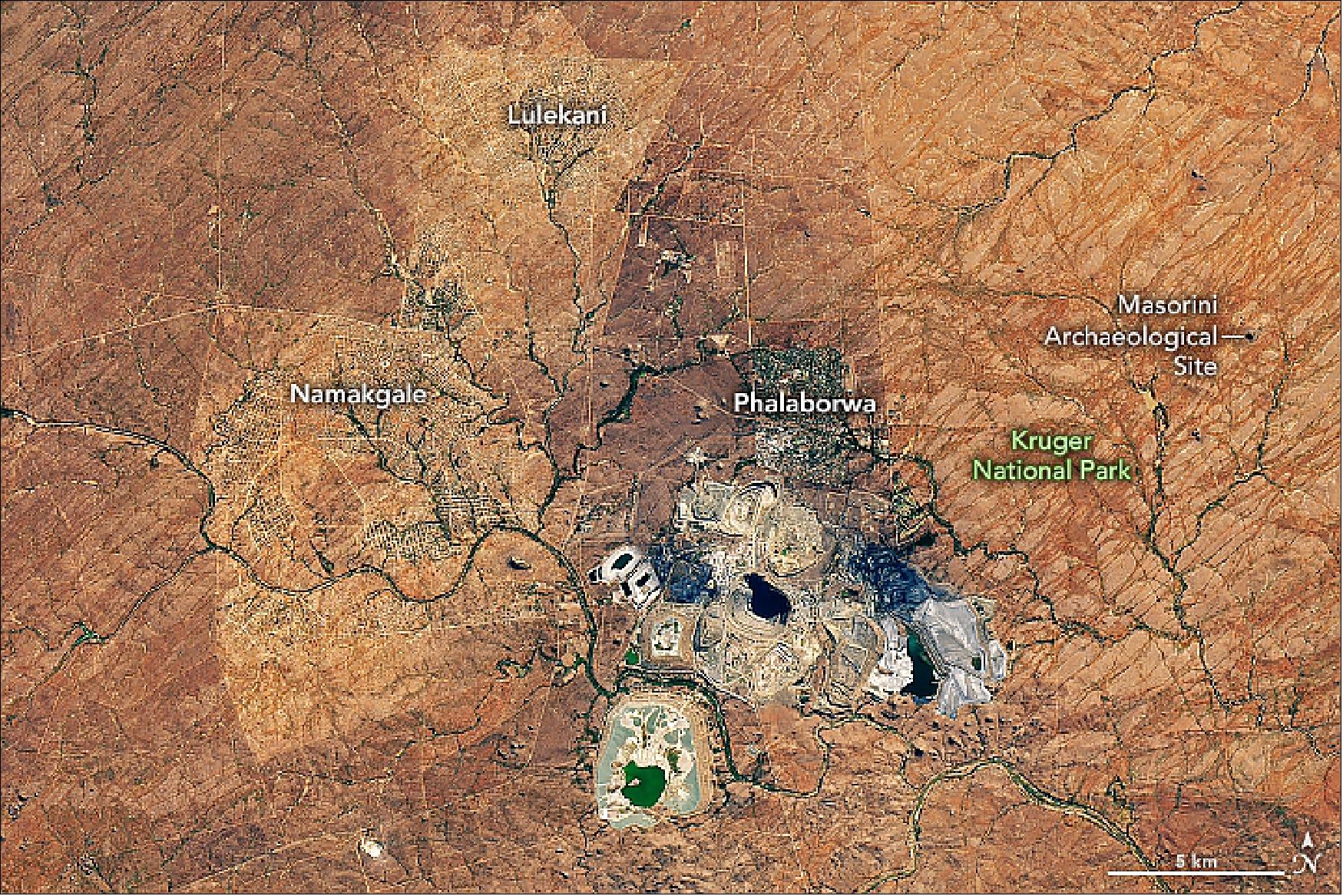 Figure 59: The pit near Phalaborwa and Kruger National Park is the most visible sign of a long history of mining in the region. The mine pictured here has been growing vertically and horizontally near Phalaborwa, South Africa, for more than 50 years. The Operational Land Imager (OLI) on Landsat 8 acquired this image of the Palabora mine on July 2, 2019. It is South Africa’s largest open-pit mine, measuring almost 2 km wide. It is about half the width of the world’s largest open-pit mine, which is at Bingham Canyon in Utah (image credit: NASA Earth Observatory image by Joshua Stevens and Allison Nussbaum, using Landsat data from the U.S. Geological Survey and topographic data from the Shuttle Radar Topography Mission (SRTM). Story by Kathryn Hansen)