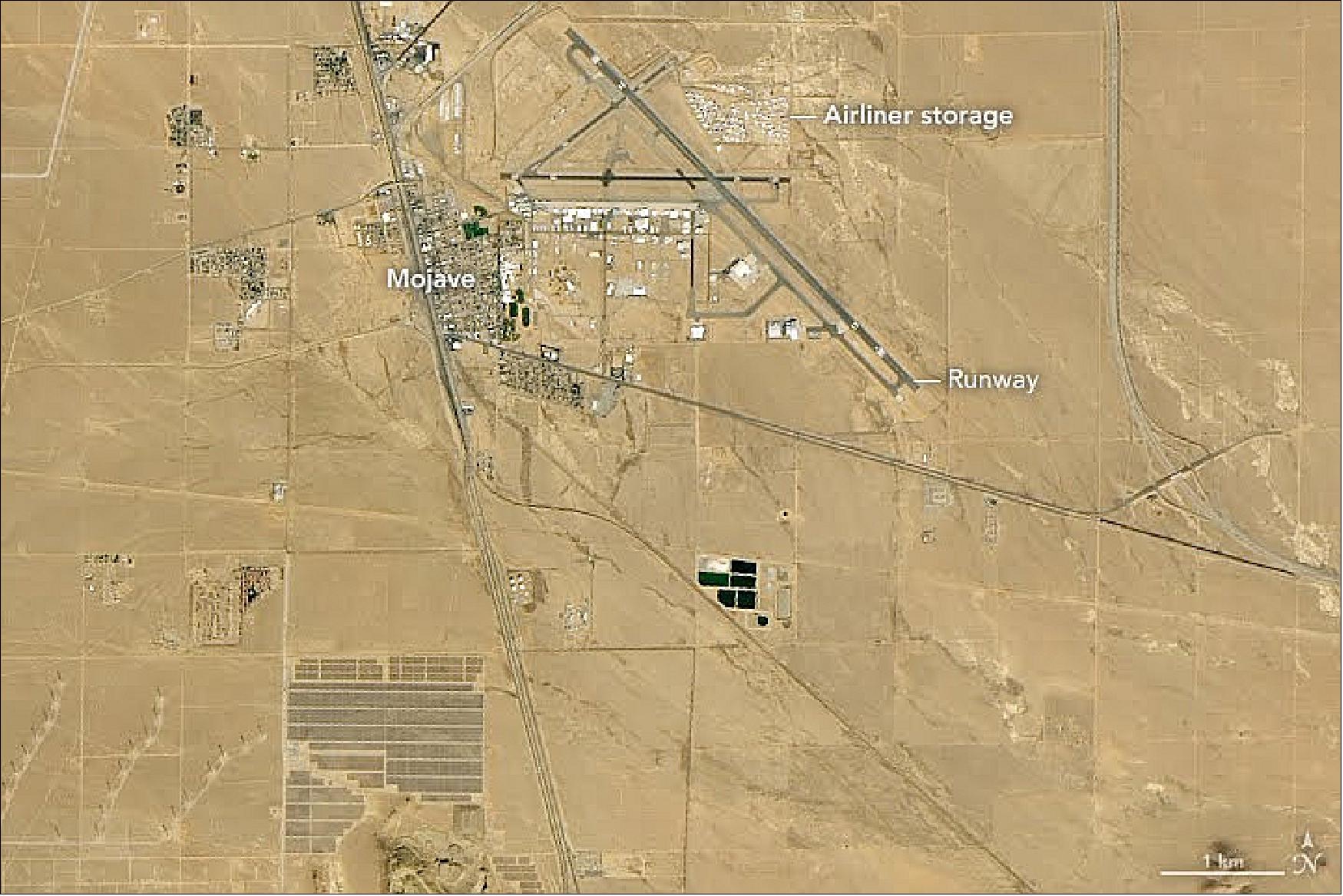 Figure 56: The Mojave Air and Space Port lies 25 km (15 miles) to the southwest. In 2004, federal authorities certified the facility as the first spaceport in the United States. Soon after, a private company launched a person into space on the rocket-powered aircraft SpaceShipOne. While experimental aircraft are a common sight, so are planes that are decades old. The air field also hosts a large storage area and boneyard for old planes (image credit: NASA Earth Observatory, image by Lauren Dauphin, using Landsat data, observed on 18 October 2018, from the U.S. Geological Survey. Story by Adam Voiland)