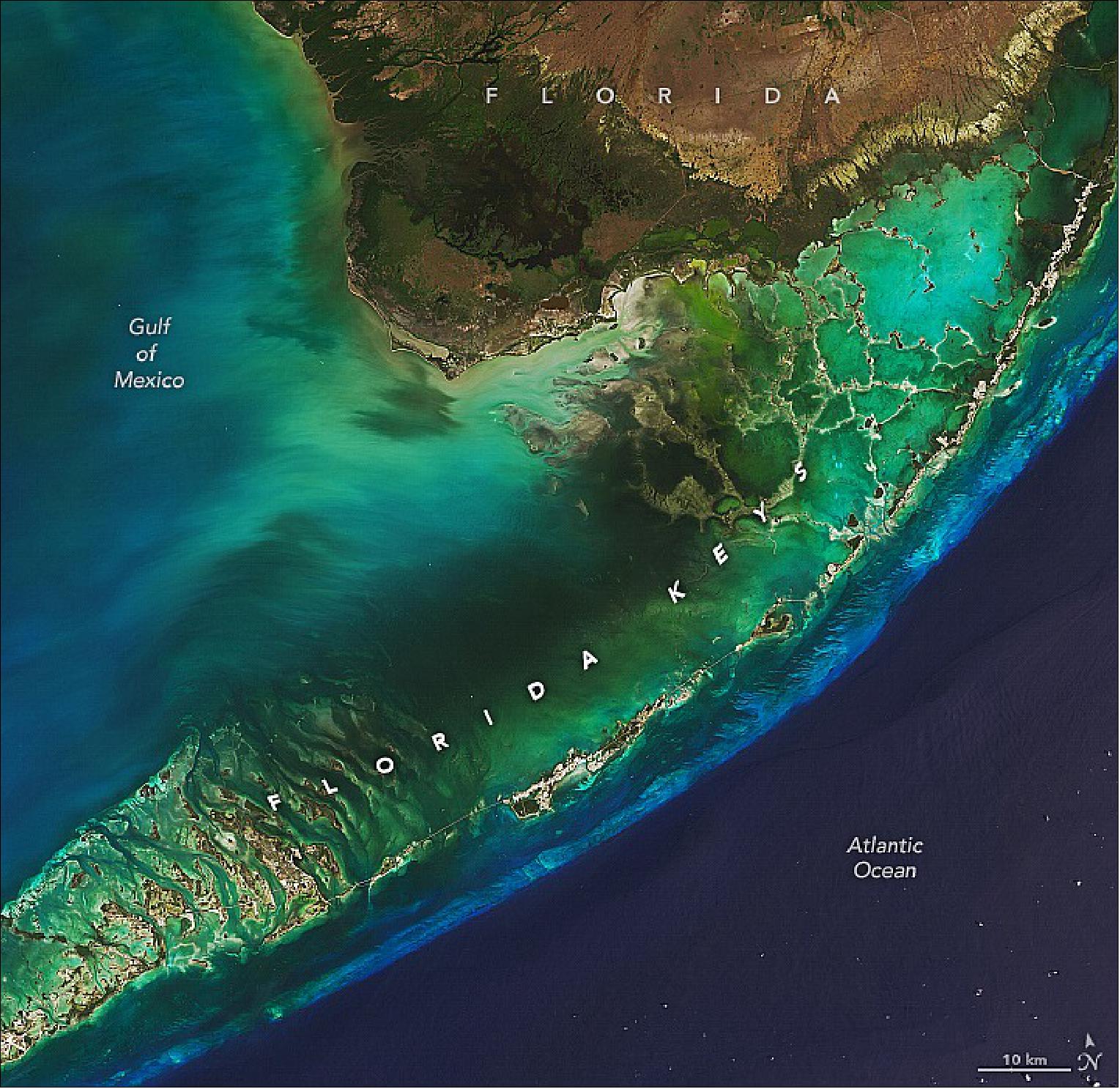 Figure 40: On March 30, 2022, the OLI instrument on Landsat-8 captured these natural-color views of the islands. North and west of the island chain, light passing through shallow waters and reflecting off the sea grass beds and sandy bottoms of Florida Bay gives this part of the scene a green-yellow hue. The light blue line south and east of the islands is a living coral reef system—among the largest in the world. Deeper water beyond the edge of the Florida platform appears dark blue (image credit: NASA Earth Observatory images by Lauren Dauphin, using Landsat data from the U.S. Geological Survey. Caption by Adam Voiland)