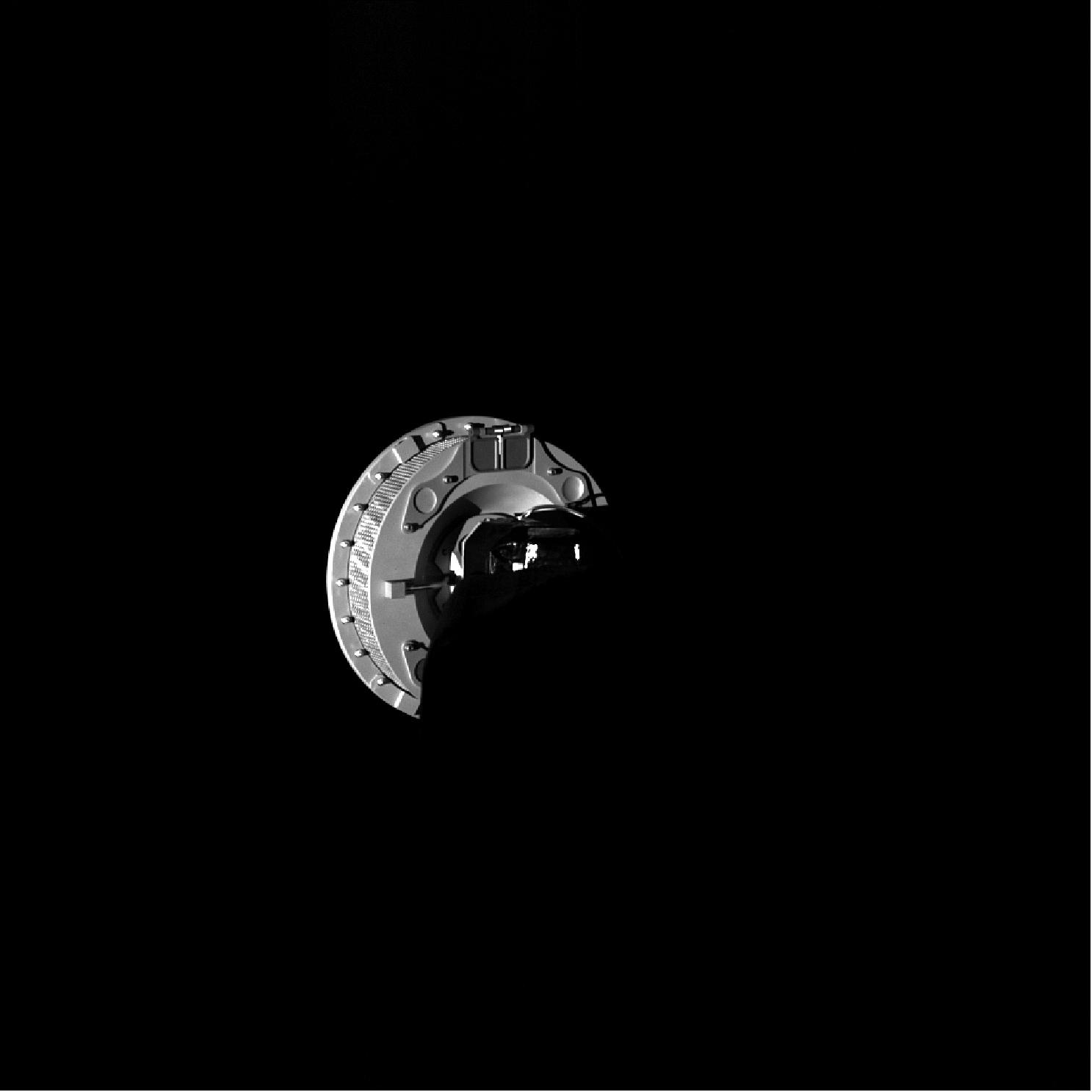 Figure 68: This image shows the OSIRIS-REx TAGSAM sampling head extended from the spacecraft at the end of the TAGSAM arm. The image was obtained by the SamCam camera on 14 November 2018 as part of a visual checkout of the spacecraft’s sample acquisition system. This is a rehearsal image for an observation that will be taken at Bennu during the moment of sample collection to help document the asteroid material collected in the TAGSAM head. There are two witness plate assemblies on the top perimeter of the TAGSAM head, one of which is entirely visible in this image. These witness plates record the deposition of material on the TAGSAM head over the duration of the mission, giving scientists a record of material on the TAGSAM head that is not from Bennu (image credit: NASA/Goddard/University of Arizona)