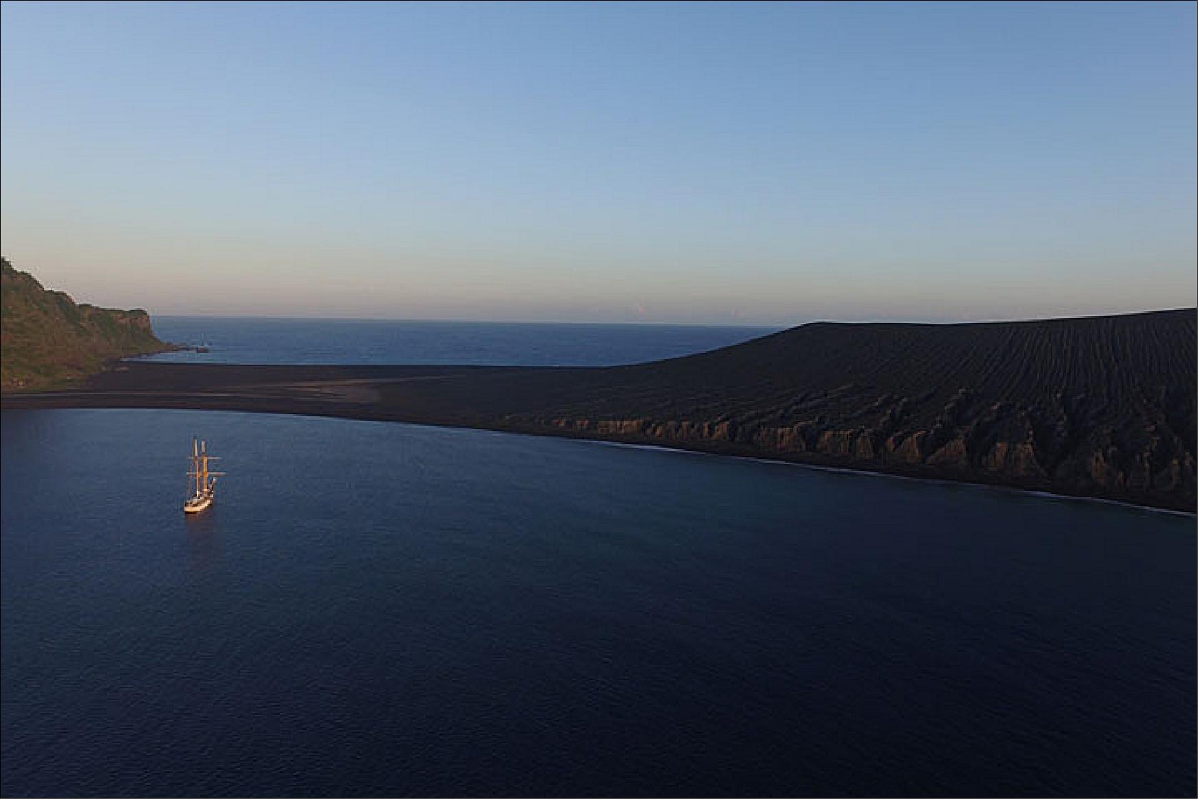 Figure 4: This photograph, acquired via drone by Captain Chris Nolan, shows the ship anchored near the island during sunset in October 2019 (photograph courtesy of Captain Chris Nolan (Sea Education Association) of the SSV Robert C. Seamans. Story by Kathryn Hansen)