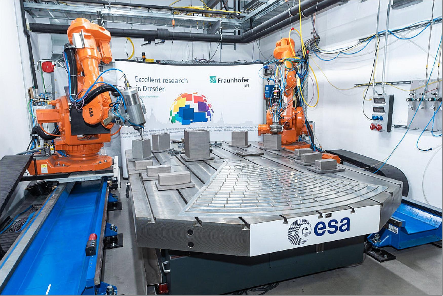 Figure 73: Technology image of the week: twin robotic arms work together to 3D print and mill a test version of the optical heart of ESA’s Athena X-ray observatory (image credit: Fraunhofer IWS)
